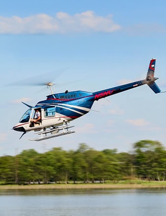 Blue White Utility Helicopter Flying Low Over Lake
