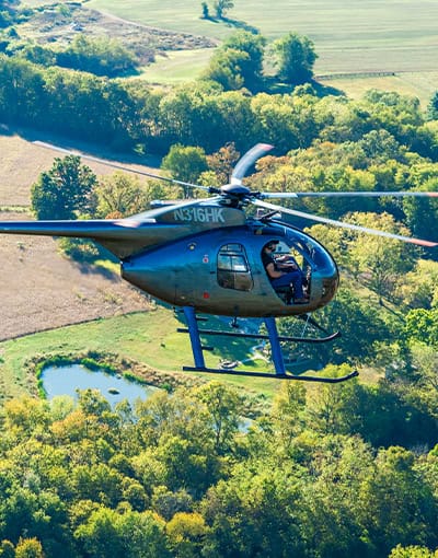 Dark Utility Helicopter Flying Over Rural Farmland And Forest