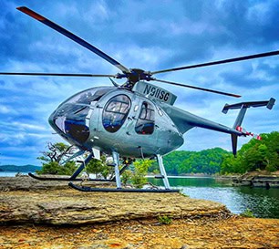 Silver Light Utility Helicopter Landed On Rocky Lakeshore