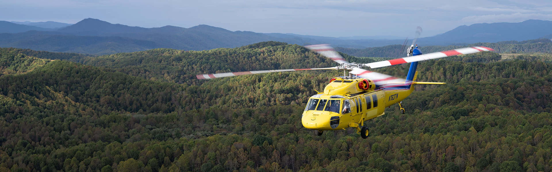 Yellow Helicopter Flying Over Mountains